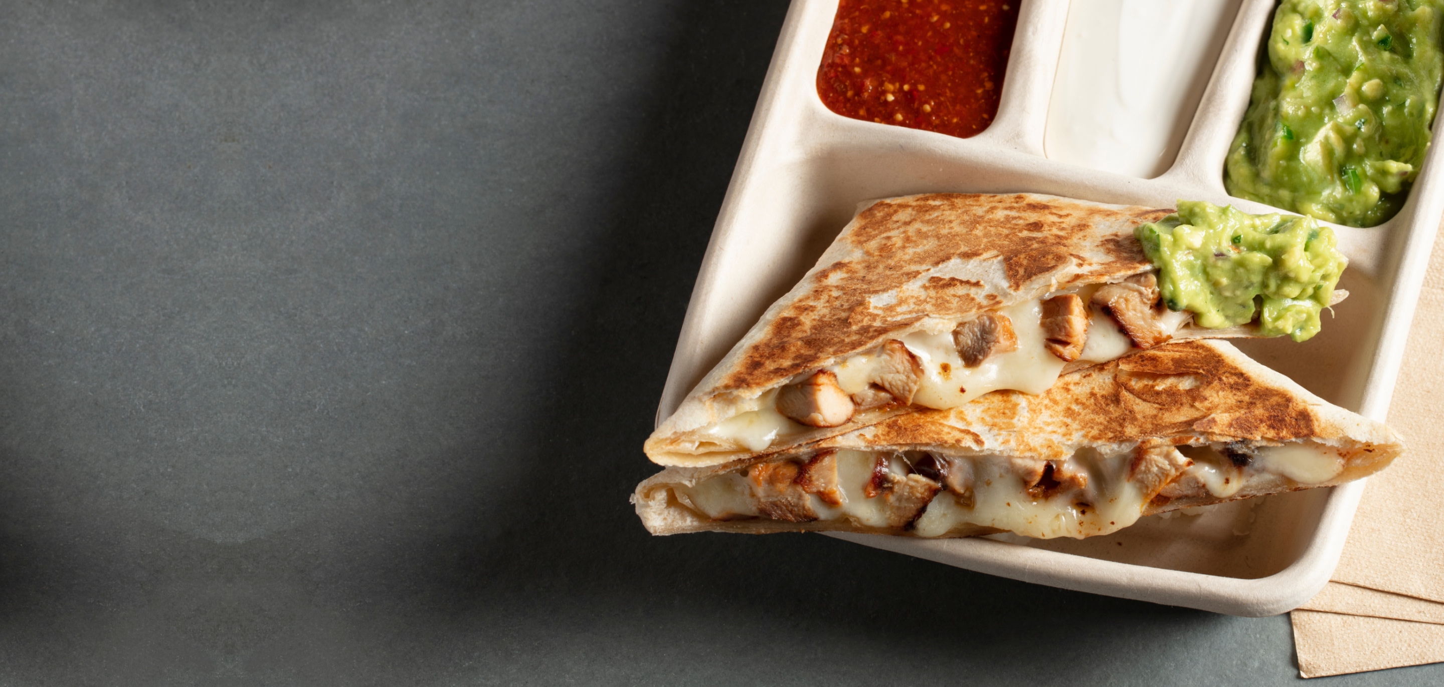 A freshly made to order Chicken Fajita Quesadilla with a side of fresh made Guac, Sour Cream, and Fresh Tomato Salsa.