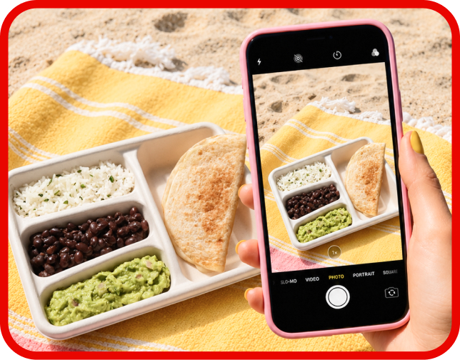 A smart phone taking a photo of the Salish Matter Kid’s Meal on a yellow towel on the beach.