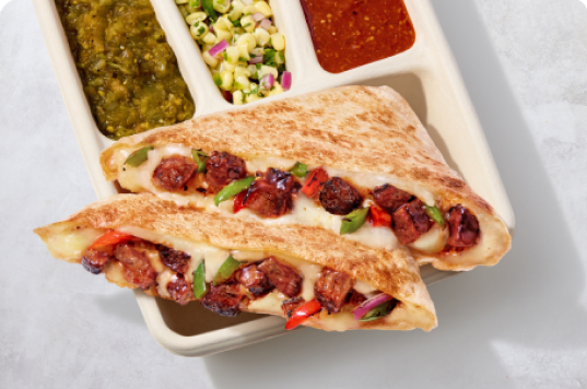 A Smoked Brisket Quesadilla with hand-chopped Smoked Brisket, melted monterey jack cheese, and fresh fajita veggies with a side of tomatillo green chili salsa, roasted corn salsa, and tomatillo red chili salsa.